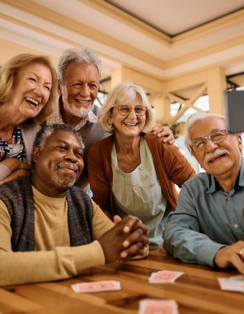 Multiracial group of happy senior people taking selfie with cell phone in nursing home.